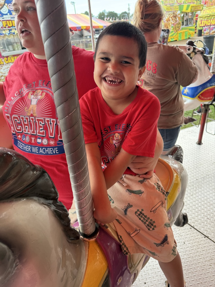 Students from Mrs. Alexis’s CDC class smiling while riding the carousel at the fair,