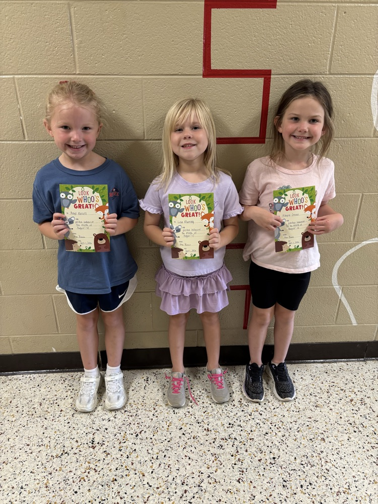 Three students standing together and holding certificates recognizing perfect behavior for the month of August.