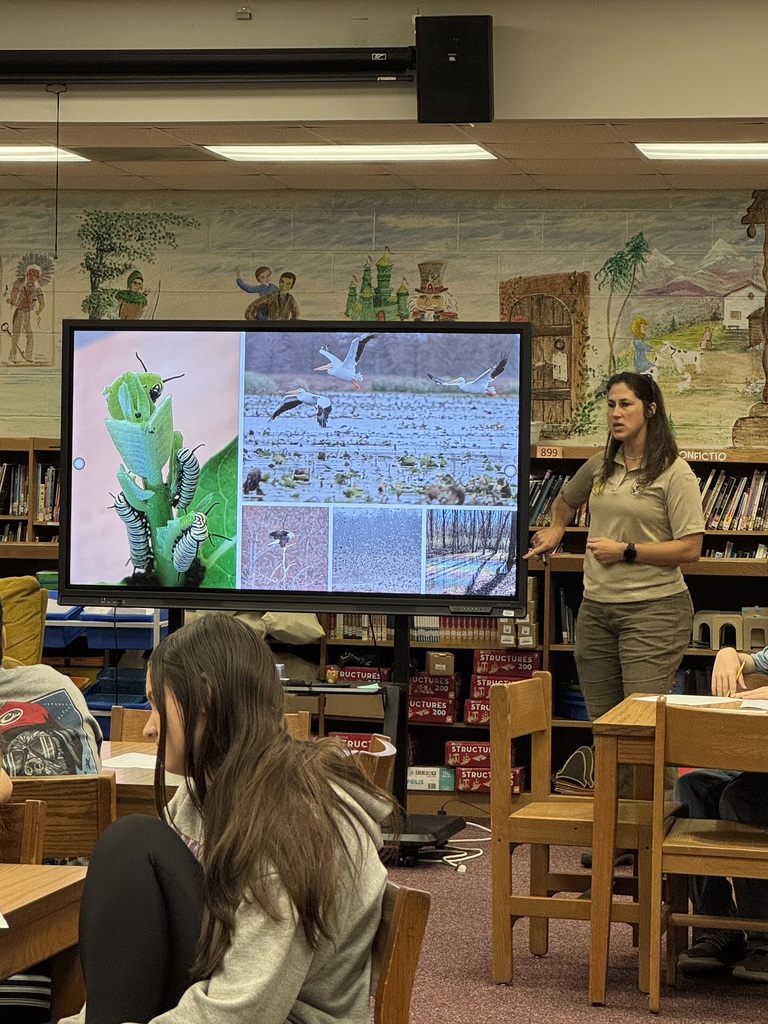 Image of a woman showing a picture of wildlife to some students.