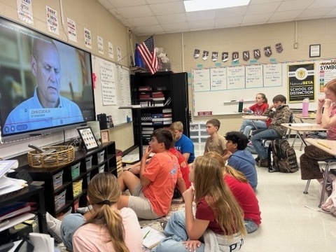 Sixth-grade students sit together in the classroom while watching an interview about the events of September 11, 2001.