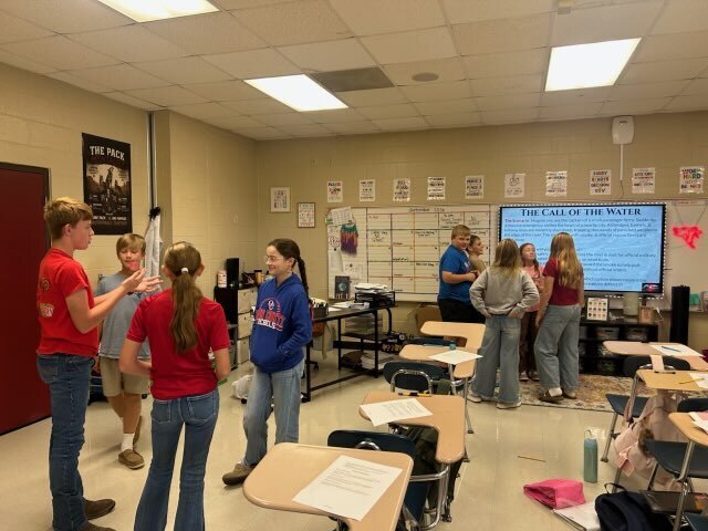 Sixth-grade students work in small groups to discuss a scenario and make decisions together.
