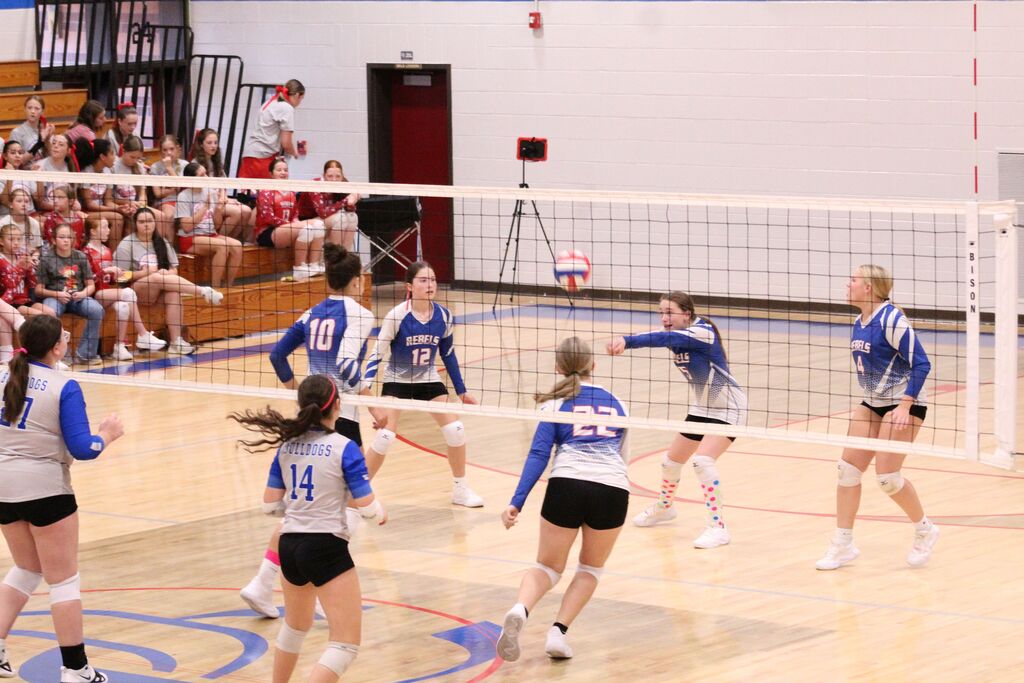 OCMS Volleyball player hits the ball while other players watch.