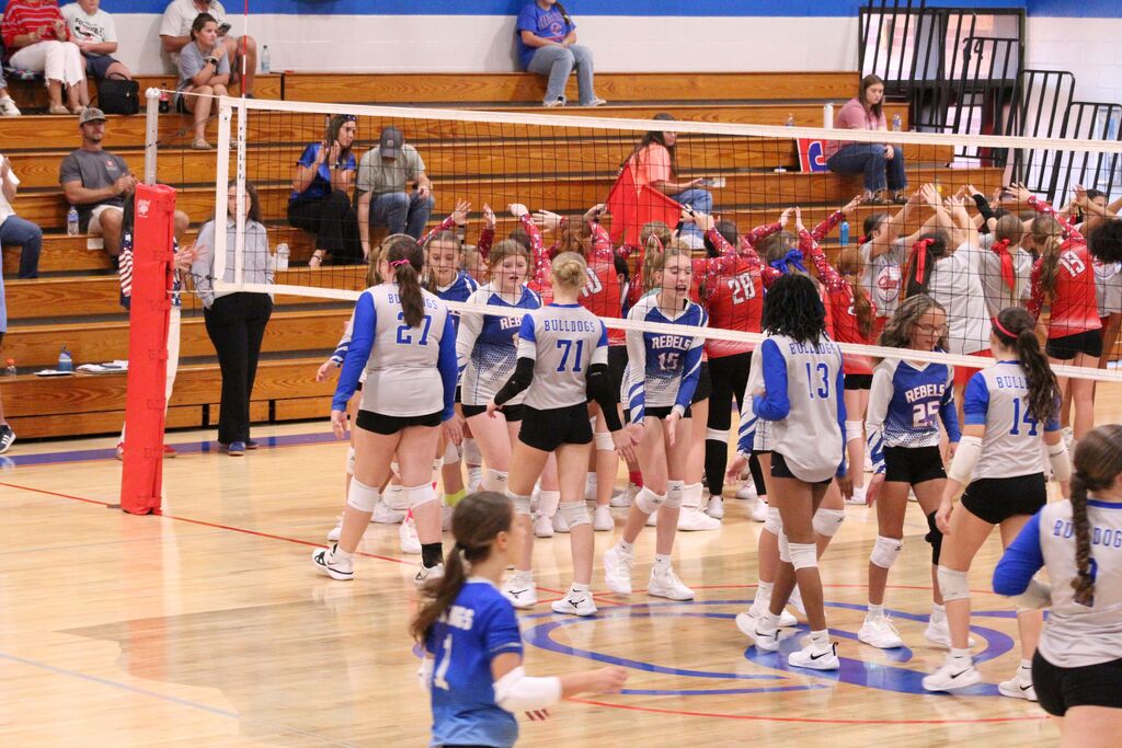 OCMS and Paris-Inman Volleyball teams shake hands at the net before volleyball game.