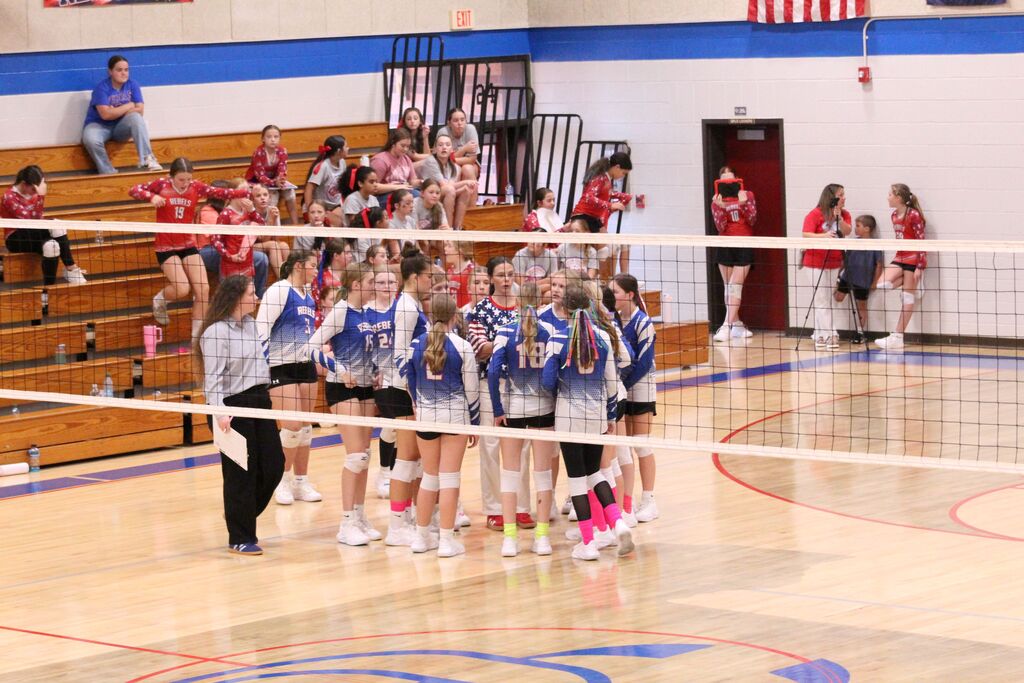 OCMS Volleyball players and coaches gather in a huddle to discuss play during volleyball game.