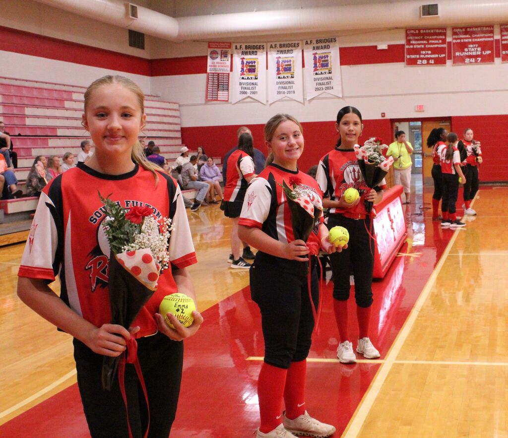 3 South Fulton Softball players smile while holding flowers and softballs.