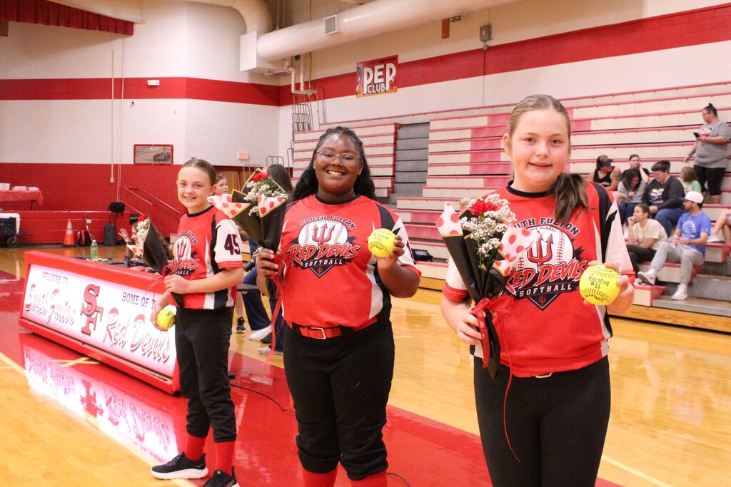 3 South Fulton softball players smile while holding flowers and softballs.