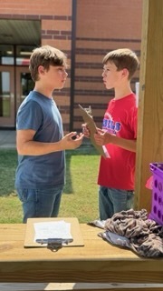 Two OCMS students discuss their class activity while standing outdoors.