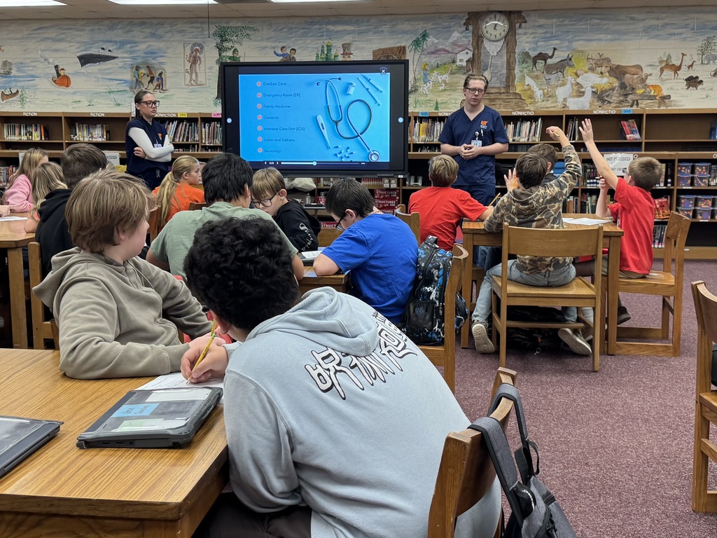 UTM nursing students speak to OCMS students about careers in nursing as students listen, take notes, and raise their hands.