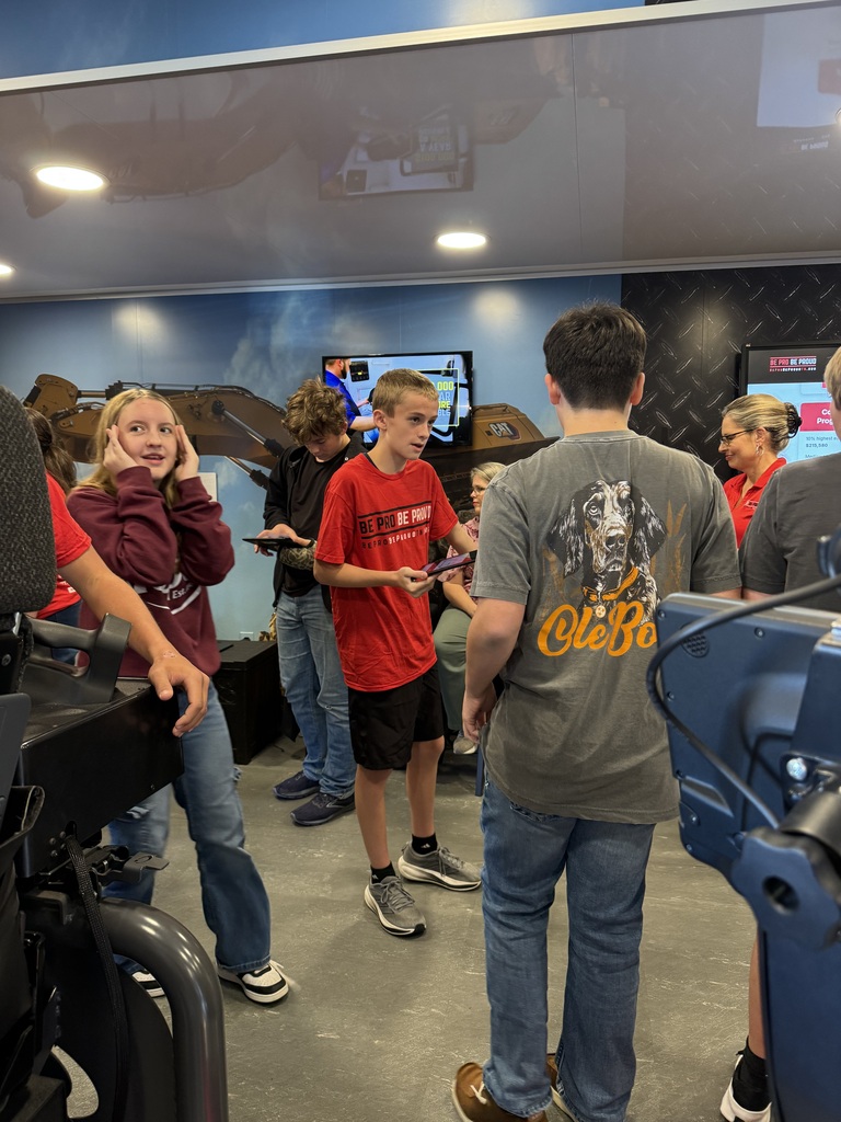 Students and ambassadors gather among simulator stations inside the Be Pro Be Proud mobile workshop to explore hands-on career activities.