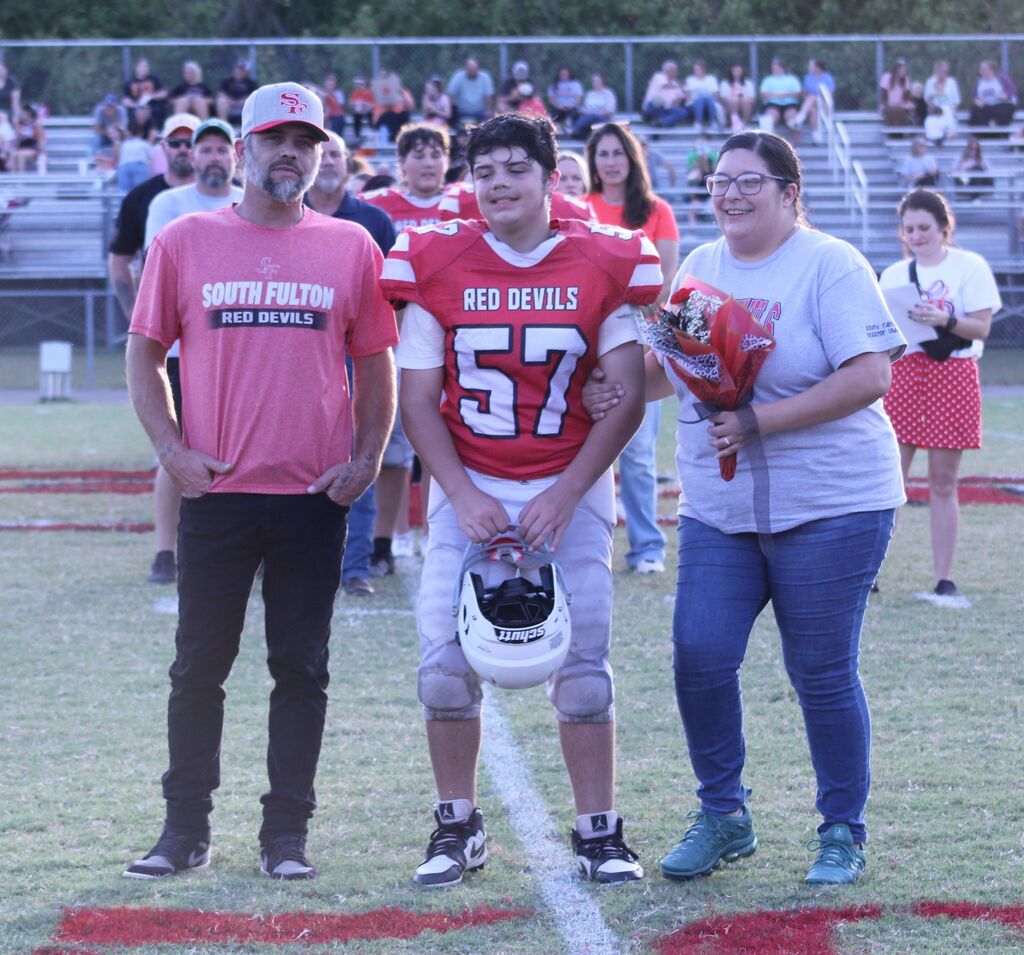 A SFMS football player smiles with his parents.