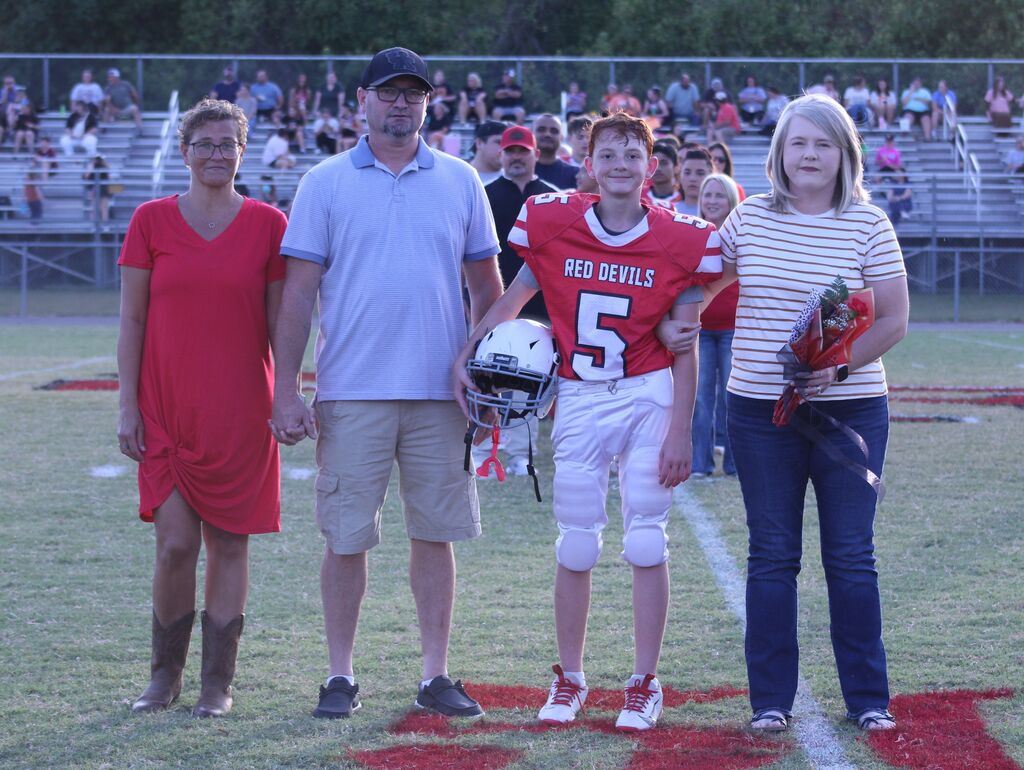 A SFMS football player smiles with his parents.