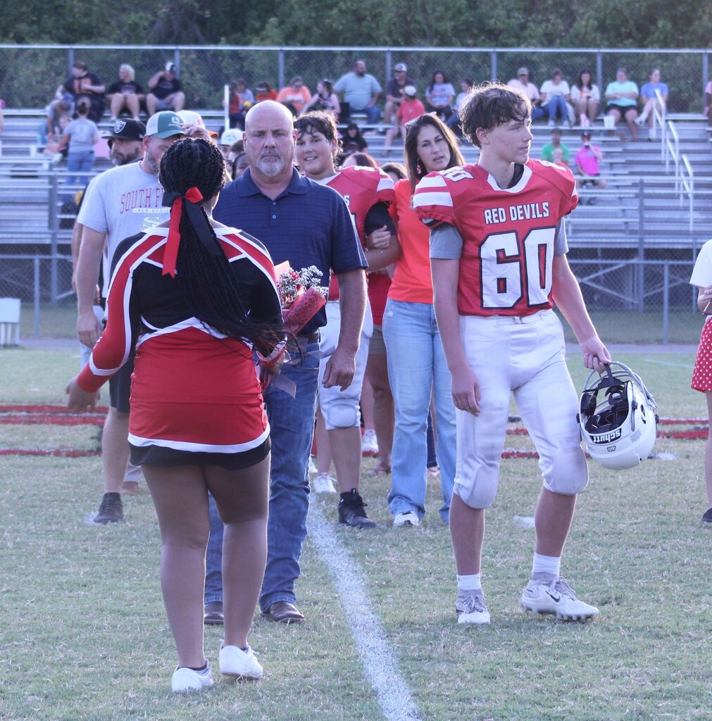 A South Fulton Middle School cheerleader presents flowers to an 8th grade football player and his parent.