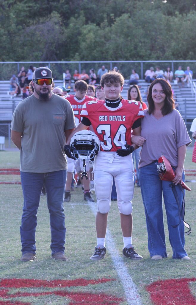 A SFMS football player smiles with his parents.