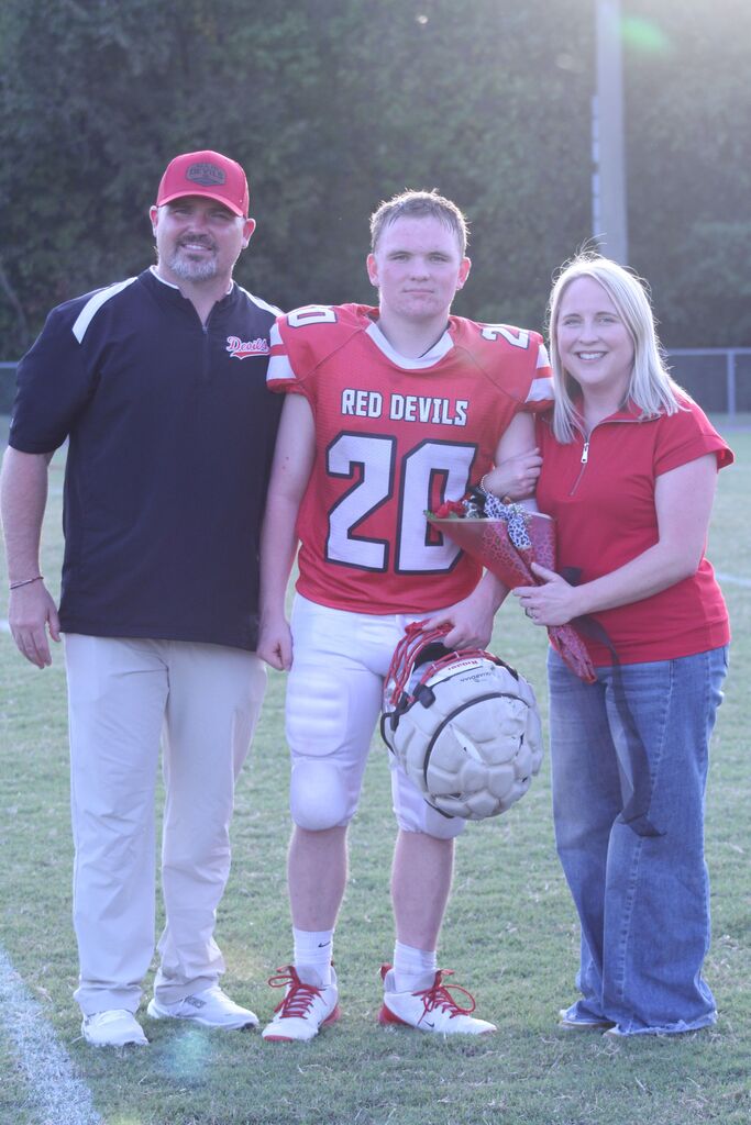 A SFMS football player smiles with his parents.