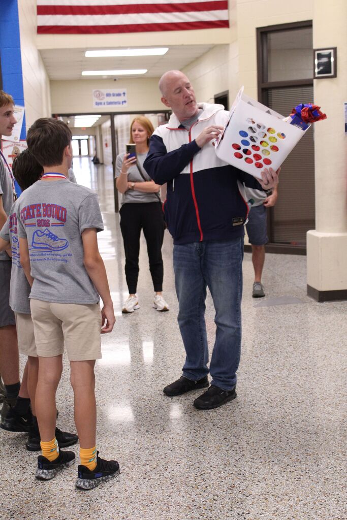 OCMS Principal, J.B. Suiter, presents a snack basket to the Cross Country team before they leave for state.