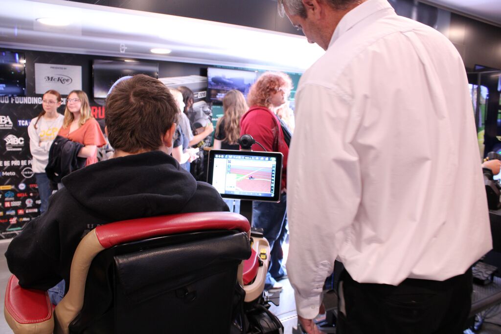 An instructor assists a student with the tractor simulator on the Be Pro, Be Proud truck.