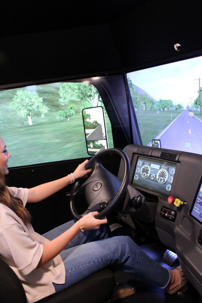 An OCCHS student uses the large truck driving simulator on the Be Pro, Be Proud truck.