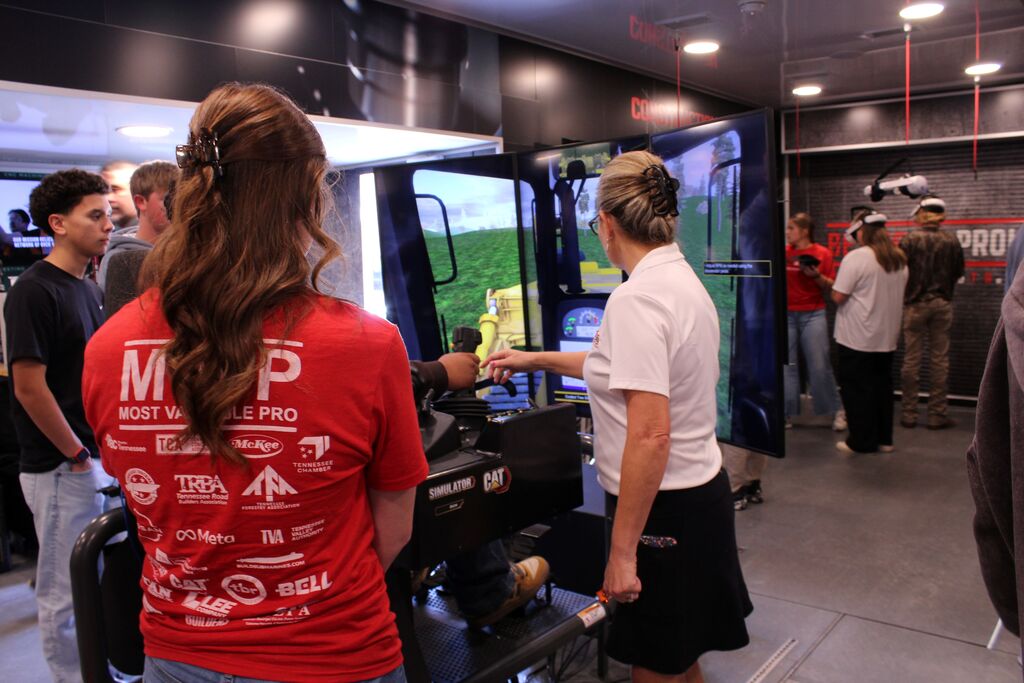 An instructor assists a student with the tractor simulator on the Be Pro, Be Proud truck.