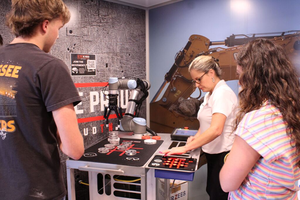 A female instructor explains how to work the robotic arm on the Be Pro, Be Proud truck.