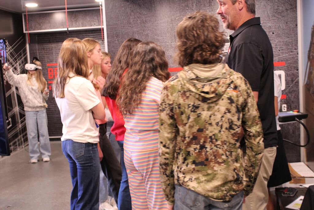A group of students look on as an instructor explains about the robotic arm on the Be Pro, Be Proud truck.