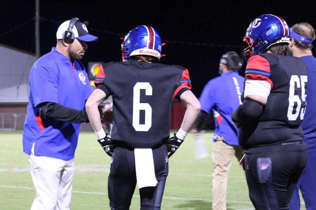 OCCHS coach gives direction to two players during homecoming football game.