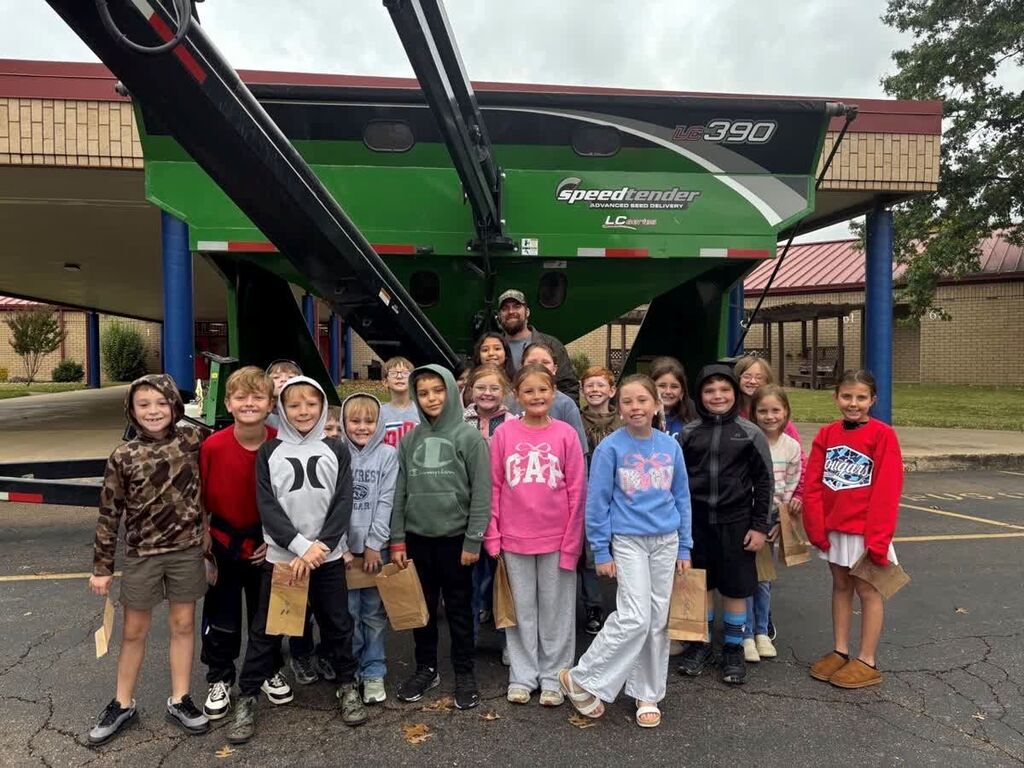 A group of Hillcrest students and a community volunteer gather in front of farm equipment at Careers on Wheels.