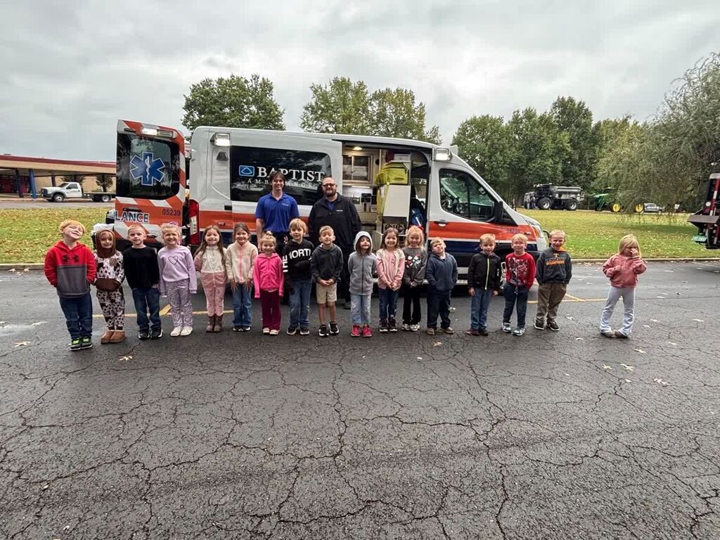 A group of Hillcrest students smile in a group in front of an ambulance and its employees at Careers on Wheels.