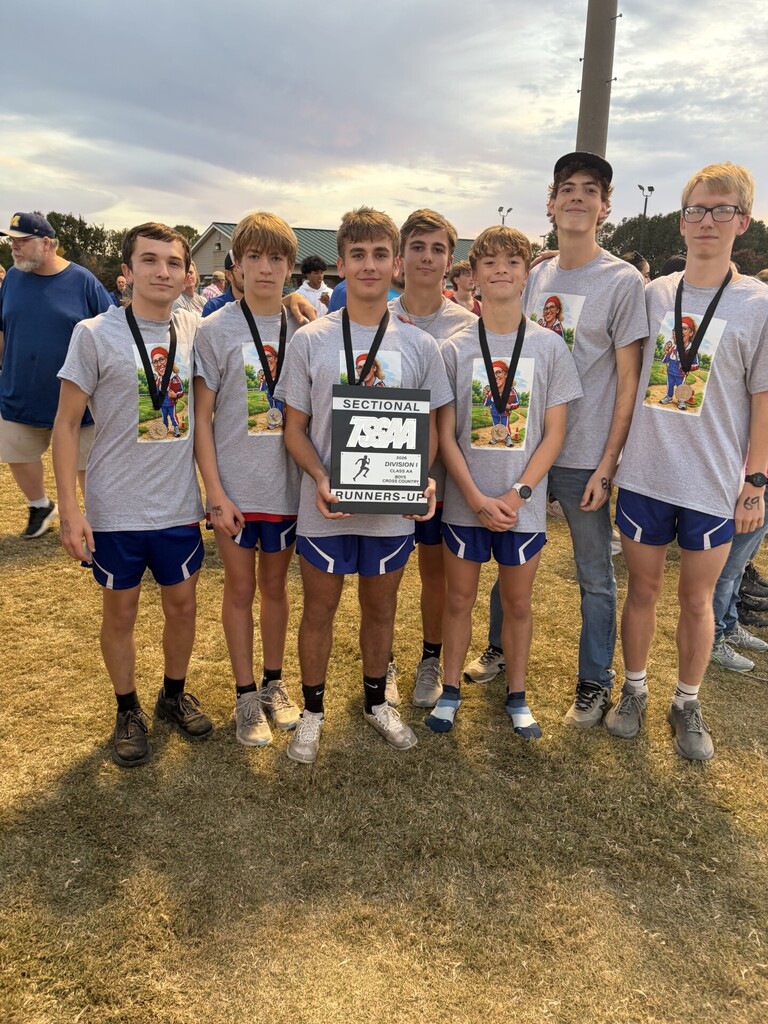 Seven OCCHS Cross Country runners from the boys' team smile with medals and a team plaque.