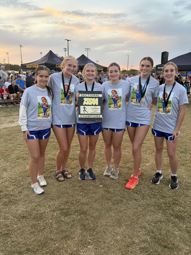 Six runners from OCCHS Cross Country girls' team smile with medals and a team plaque.