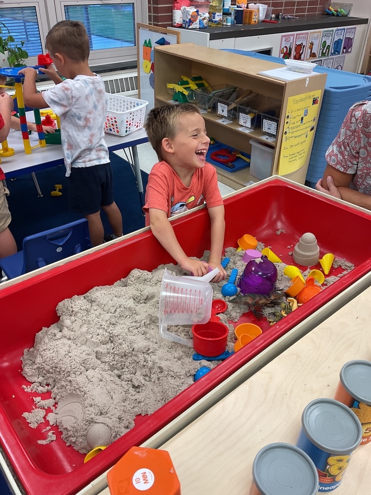 Preschool student laughing playing in a sandbox