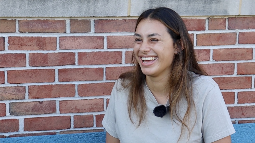 female student laughing in front of brick wall