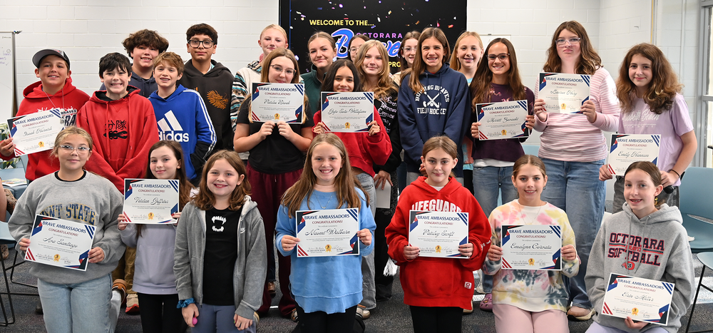 Students stand together holding certificates