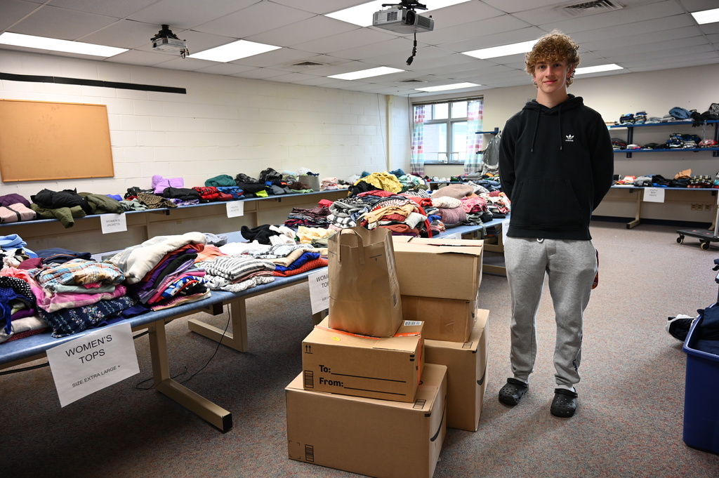 Student stands next to his donation drive for Brave Haven