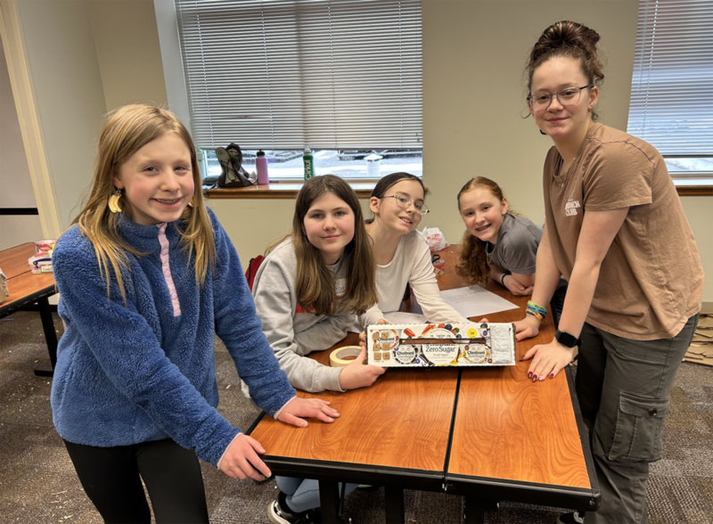 students proudly stand next to their design