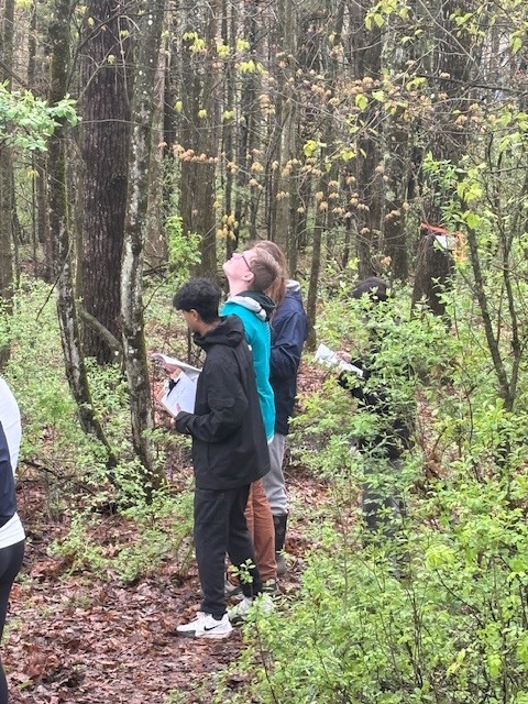 students standing together with papers on clipboards in the woods