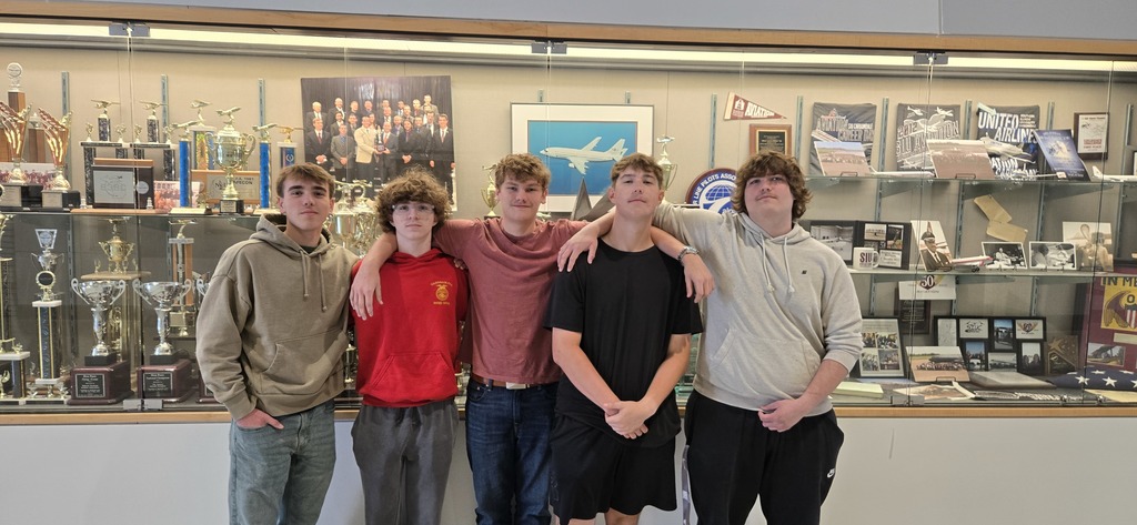 Drone class students standing in front of SIU-C School of Aviation trophy case