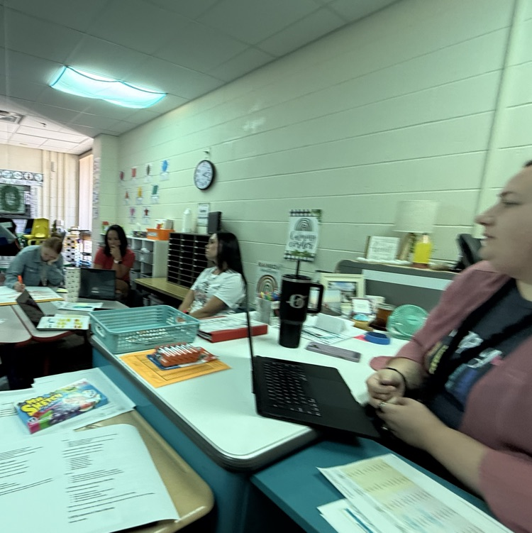 teachers sitting at table looking at papers 