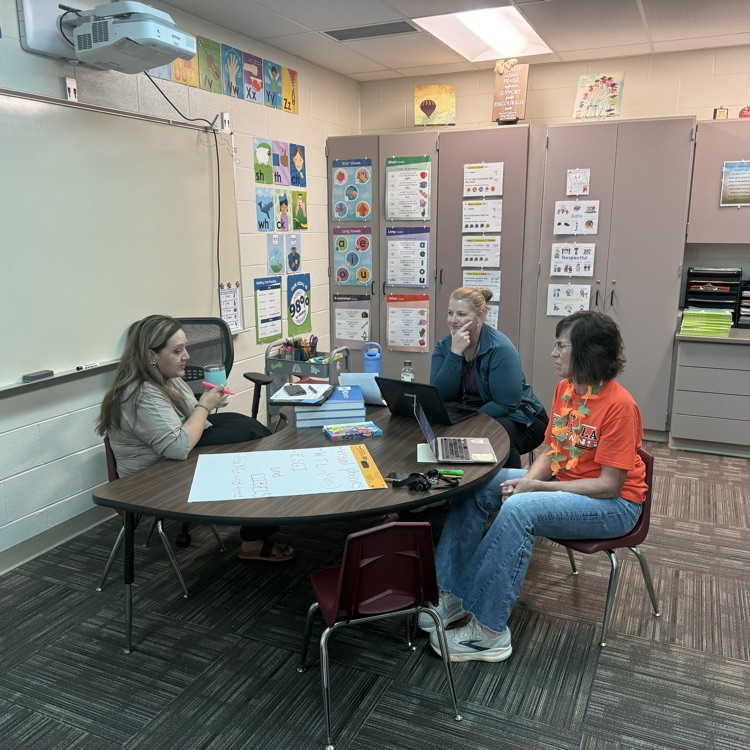 teachers sitting at table looking at papers 