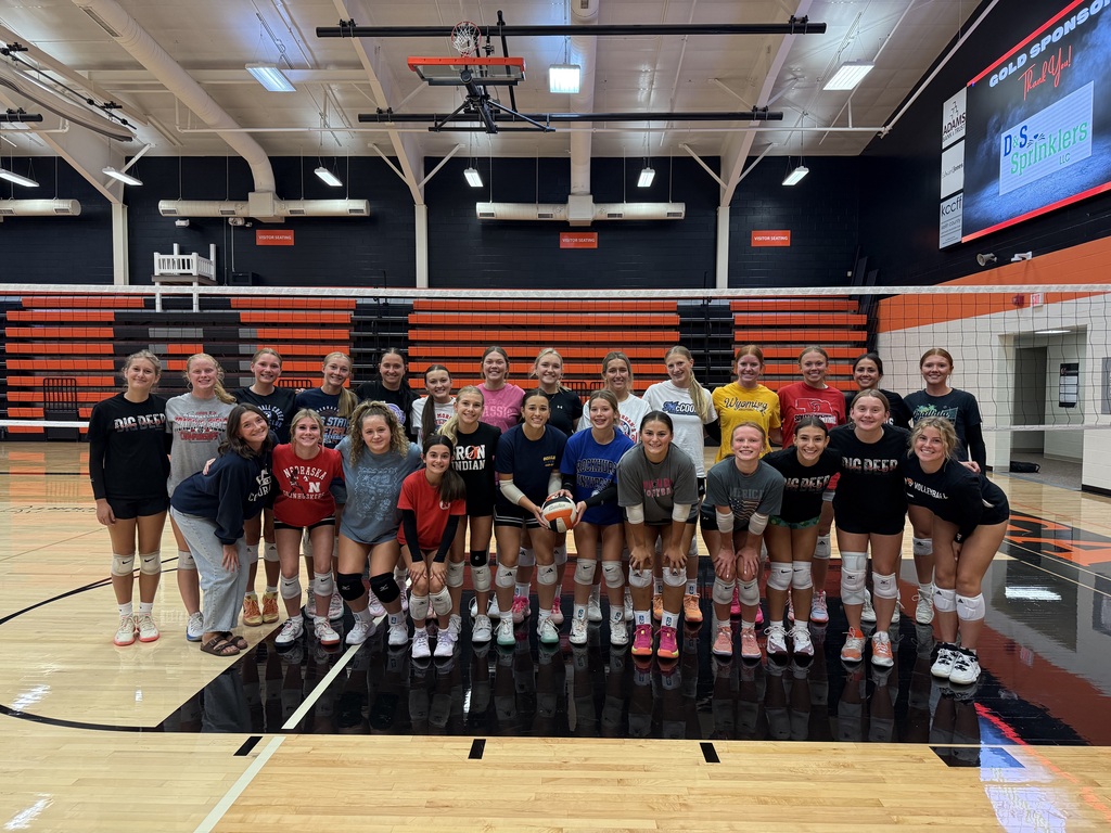 OHS volleyball team posing in front of net