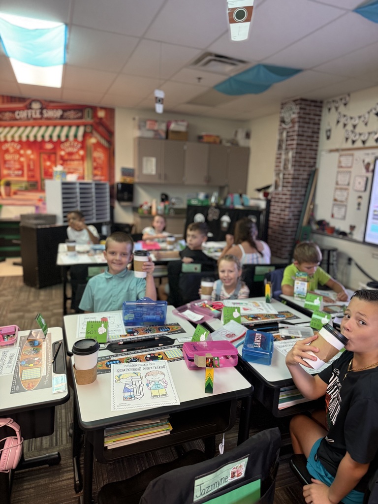 students holding chocolate milk while smiling at camera.