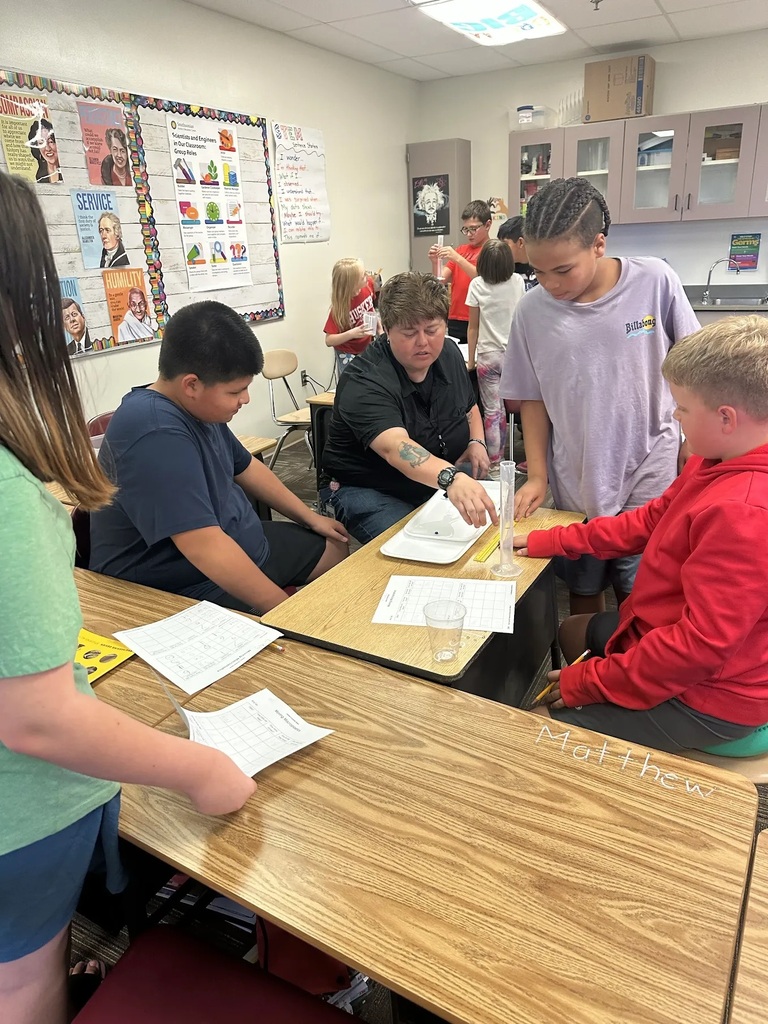students and paraeducator examining what's inside a plastic beaker