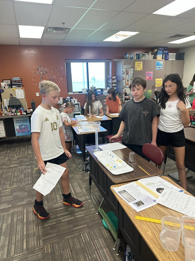students looking at plastic beaker sitting on a desk