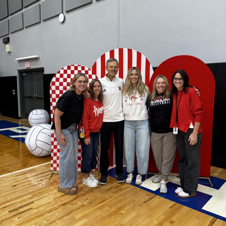 4 staff members standing with John cook in front of red and whole backdrop