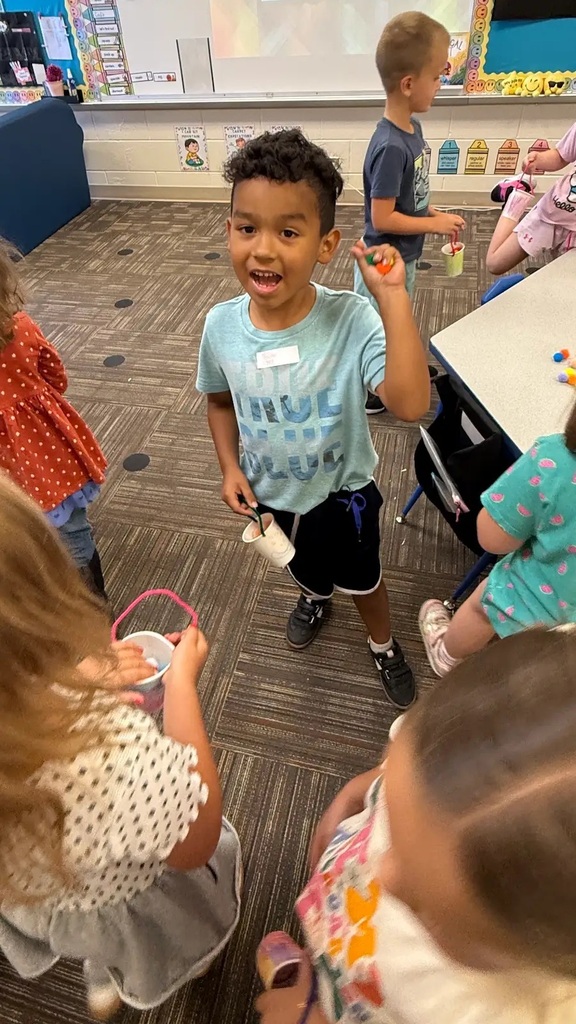students holding buckets smiling at cameras