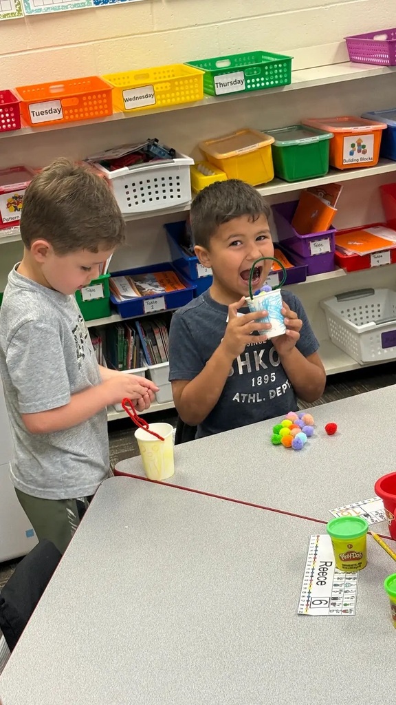 students holding buckets smiling at cameras