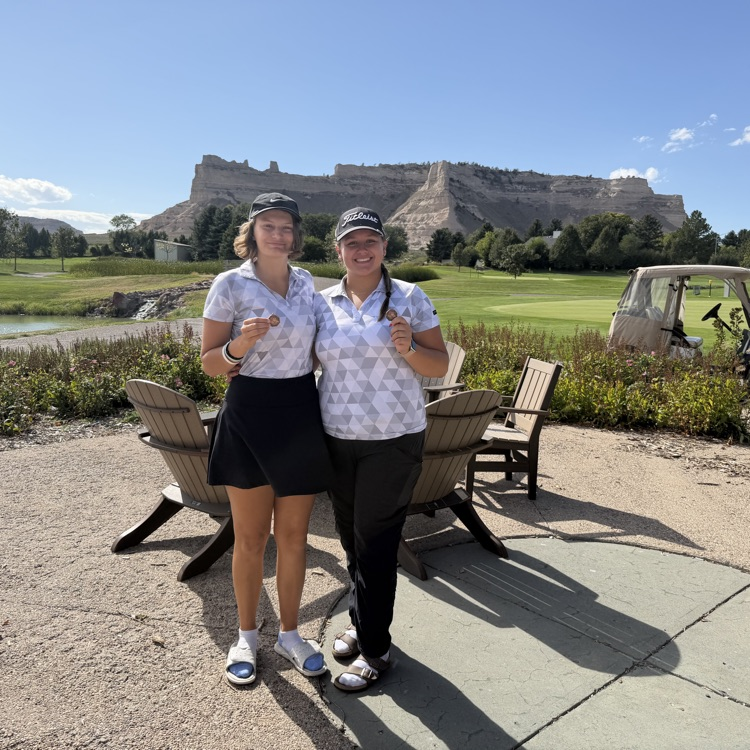 two golfers standing beside each other holding medals