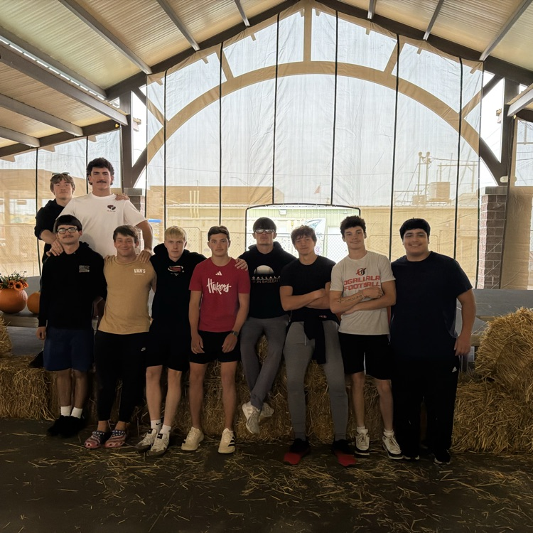 football team standing in front of hay bales 