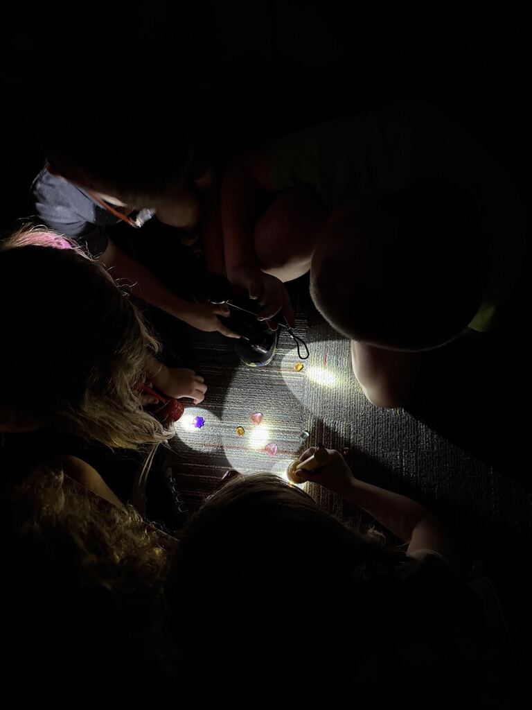 group of studnts laying on ground shining lights at gems