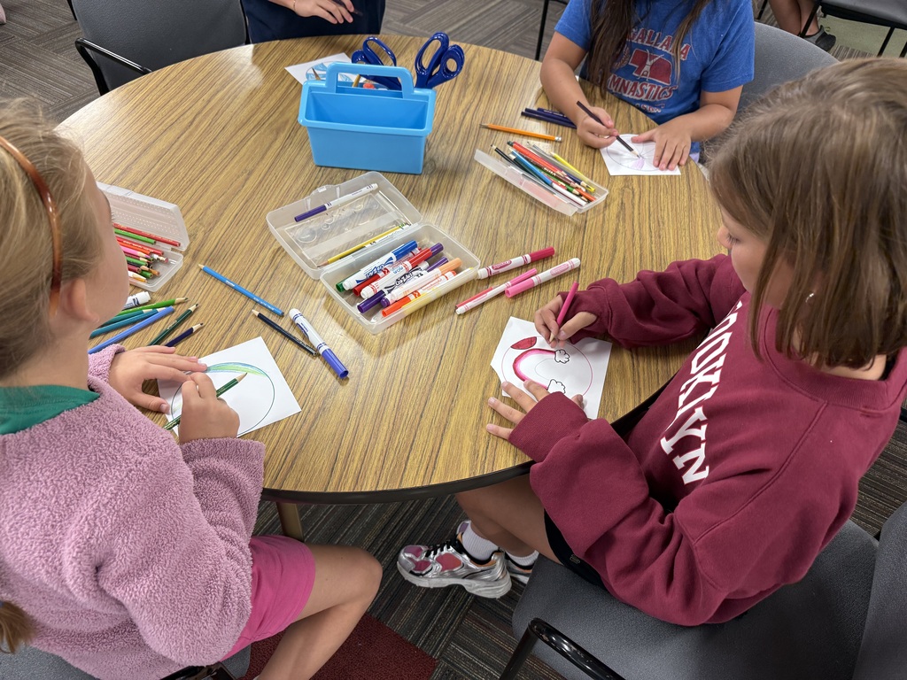 group of students coloring dots with markers and colored pencils on the table