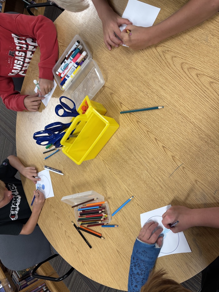 students coloring dots white dots. colored pencils scattered on table